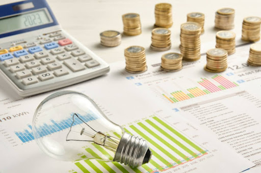 Energy bills covered by calculator, coins, and light bulb
