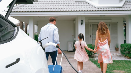 Electric vehicle being plugged in to charge as family walks home.